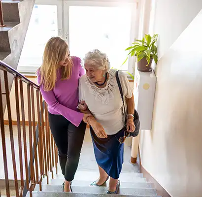 woman helping her elderly mother up the stairs